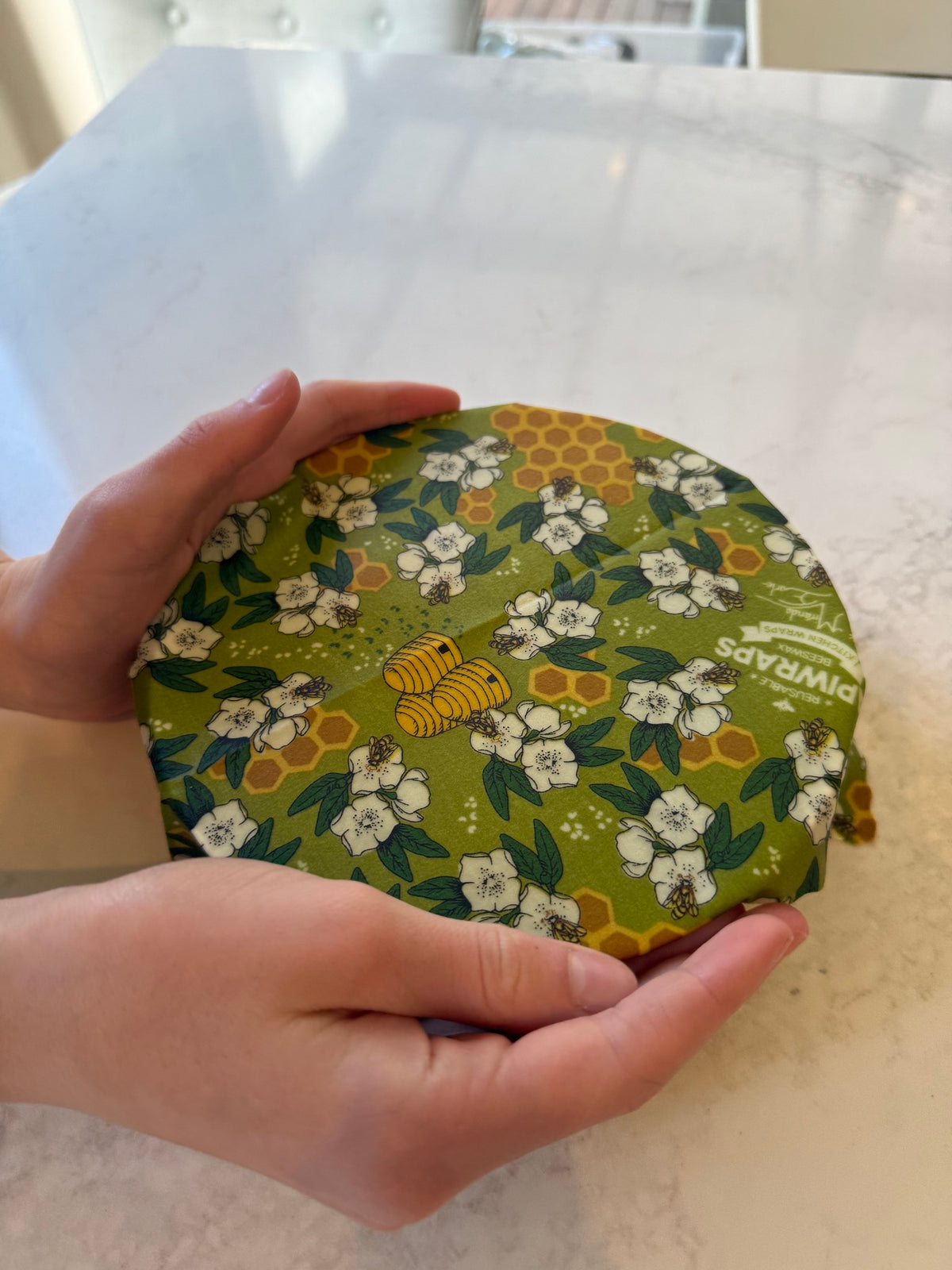 Hands warming a beeswax wrap to seal it over a bowl