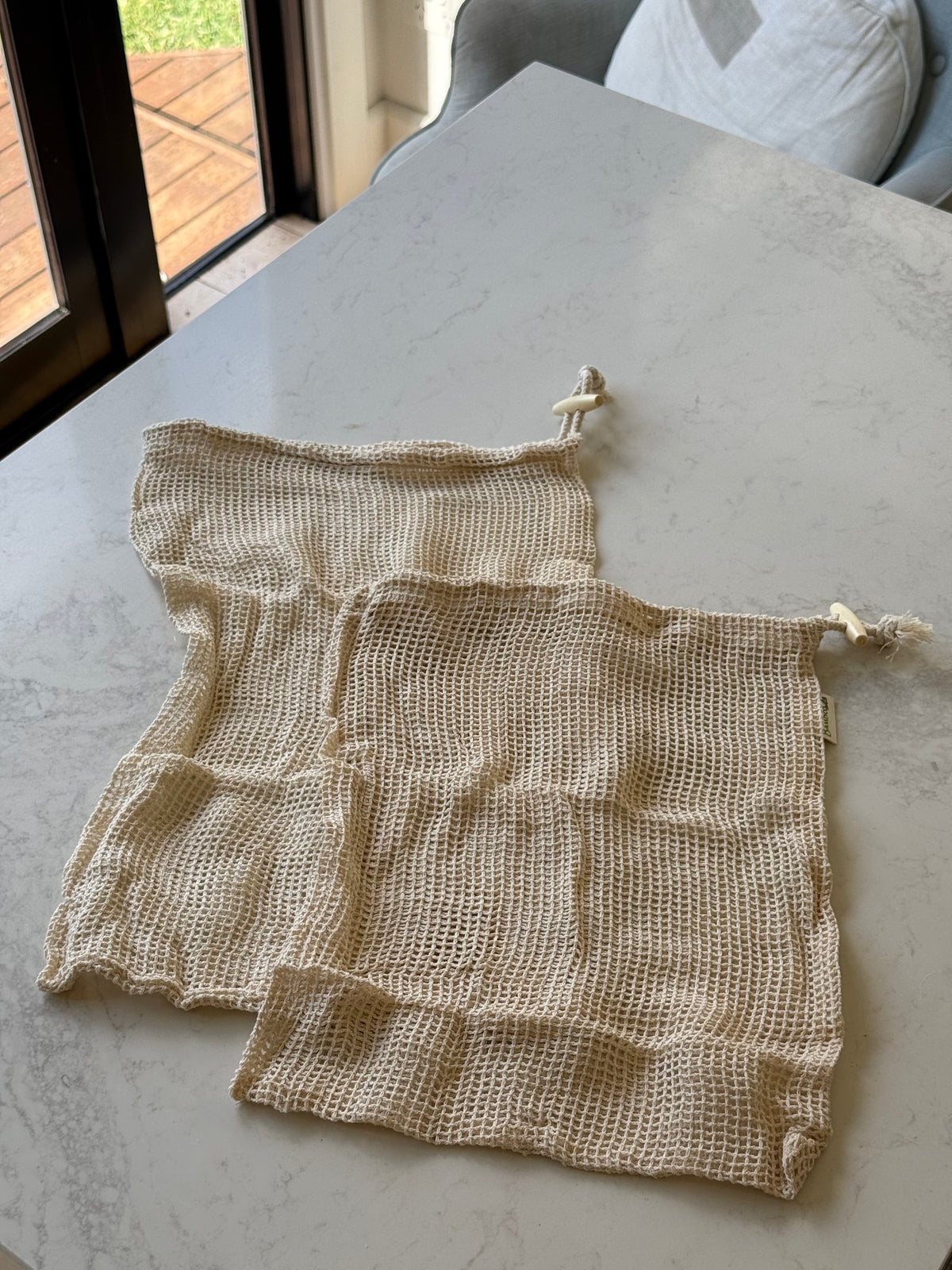 Two organic cotton mesh produce bags, medium and large, on our kitchen bench in Bayside