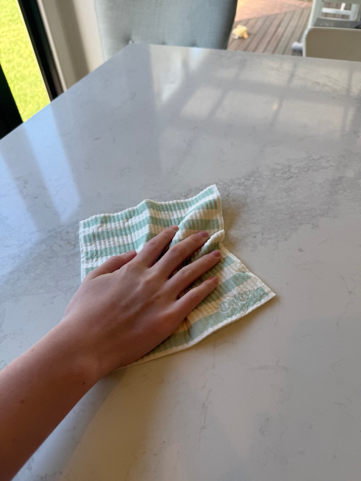Sage stripe Swedish dish cloth wiping our kitchen bench
