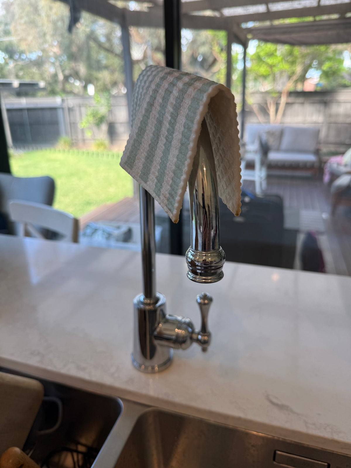 Sage stripe dish cloth drying over the kitchen tap